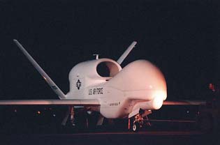 Photo of odd-looking, white jet aircraft, sitting on the ground at night.  Has a bulbous nose with no cockpit or windows, and one large jet engine on top of the fuselage in front of the large V-shaped tail.  Painted on the side is the U.S. Air Force logo and name.