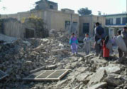 Afghan children and adults looking at the rubble of their bombed buildings.