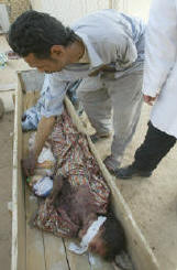 Photo of a man with short black hair leaning over the coffin touching the dead baby, which is lying next to his dead mother. A white band of cloth is wrapped around her face.