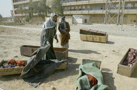 Photo of the same man pulling off the blanket which has covered one of the coffins in the street.