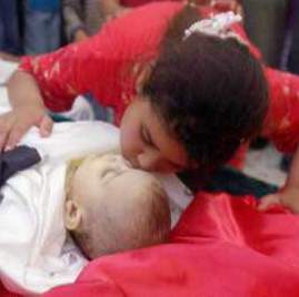 Photo shows a young Palestinian girl bending down to kiss the cheek of the dead baby.