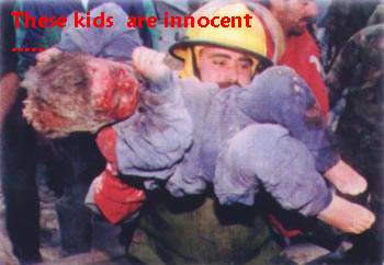 Photo shows a rescue worker wearing a yellow helmet and holding the dead body of a little boy, about three years old. There is blood all over the little boy's face and his body appears to be frozen in rigor mortis, with his knees bent and his right hand in front of his face. The caption says - 'These kids are innocent'.