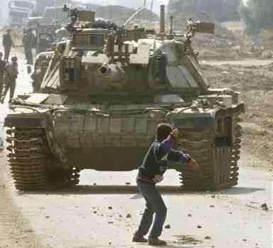 A small Palestinian boy standing before a huge Israeli tank and throwing a rock at it.