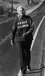 photo of a white-haired older woman  walking along the side of a highway; the words 'Peace Pilgrim' are on the front of her jersey.