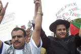 An orthodox Jewish man and a Palestinian man raising their hands together in a show of solidarity during the march and rally.